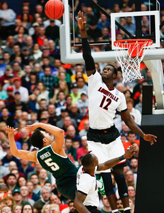 MSU's Bryn Forbes goes for a shot but falls as Lousiville's Mangok Mathiang goes for a block.