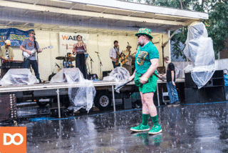 Sir Quala O’Smith dances in the rain while a rock band plays their set at the street fair.