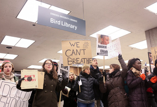 Protesters hold up signs upon their arrival to Bird Library, where they held a 