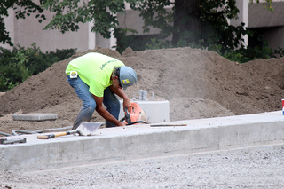 A construction worker makes repairs on the side of what will soon be the University Place promenade. Photo taken July 28, 2016