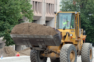 A construction vehicle moves piles of dirt along the University Place promenade. Photo taken July 28, 2016